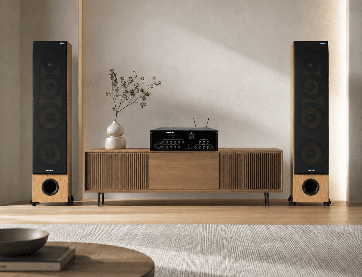 Cặp loa cột Nikochi và amply đặt trên kệ gỗ trong phòng khách hiện đại